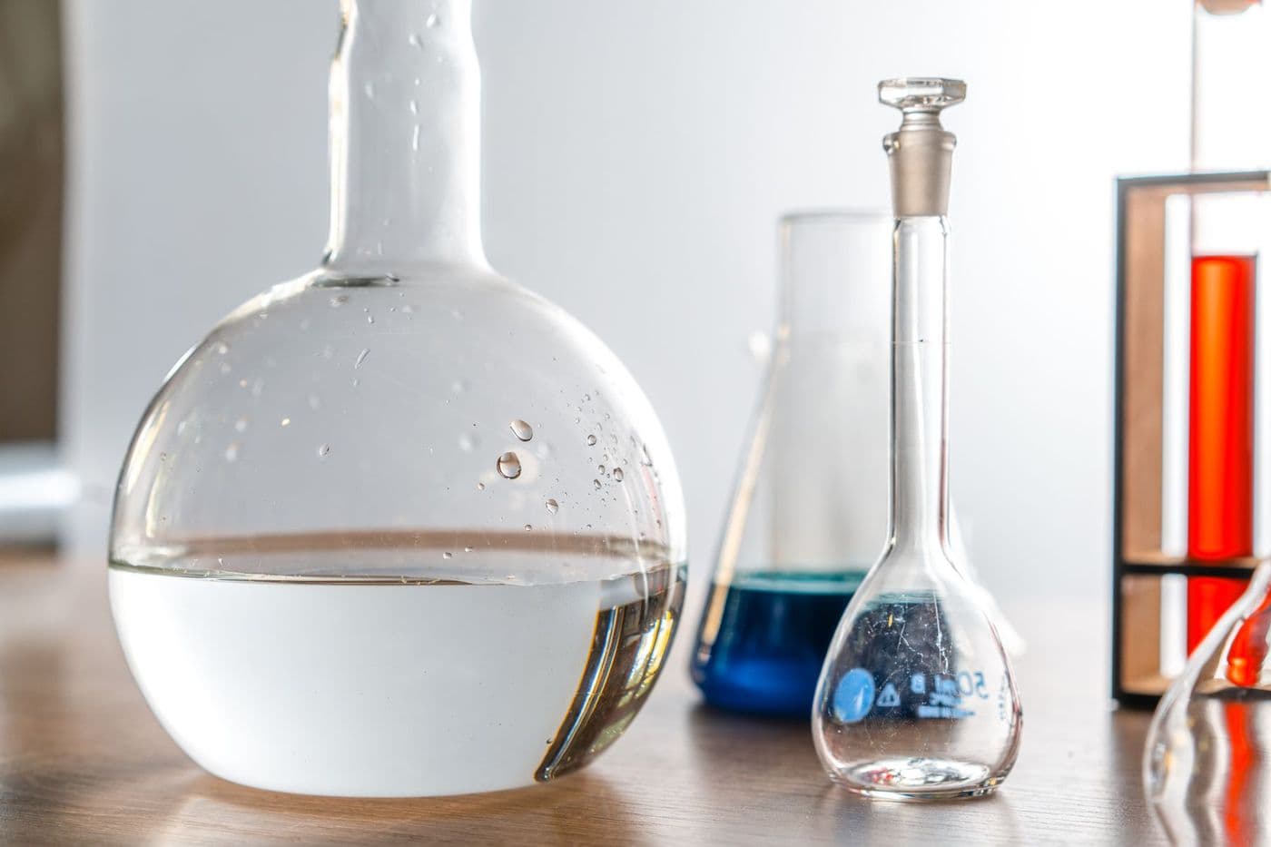 Two laboratory flasks side by side, one holding a clear solution and one coloured.