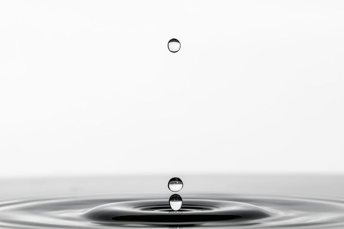 A single water droplet falling into still water.