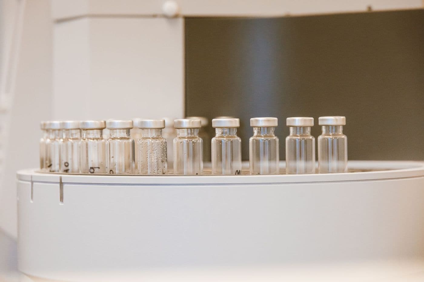 A row of crimped-cap glass vials on laboratory equipment.